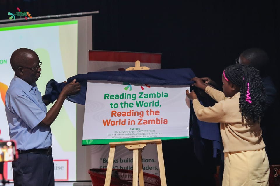 A schoolgirl and a guest unveil the board bearing the fair's theme, “Reading Zambia to the World, Reading the World in Zambia”.